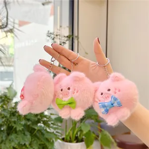 Set van drie schattige pluche varkenssleutelhangers met strikjes in een knusse setting