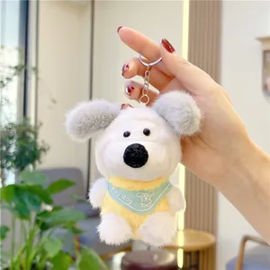 Close-up of white plush dog keychain with blue bib and silver metal ring accessory