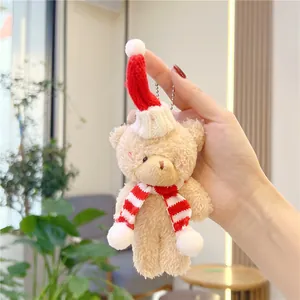Close-up of a plush Christmas teddy bear keychain with a red knit hat and striped scarf