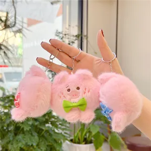 Detail van schattige roze pluche varkenssleutelhangers met borduurwerk en strikjes
