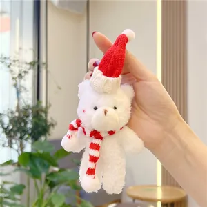 Close-up of a white plush Christmas bear keychain with a red hat and striped scarf
