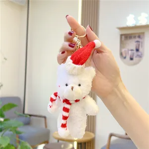 Close-up of white plush bear keychain with red Christmas hat and striped scarf