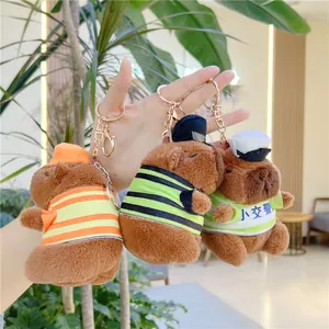 Three capybara plush keychains wearing police outfits held against a garden background
