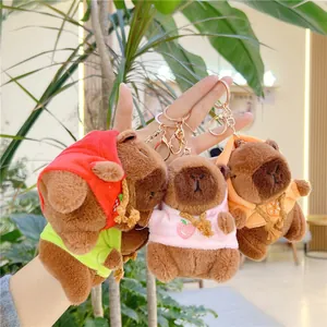 Three plush capybara keychains wearing fruit-themed hoodies in a bright indoor setting