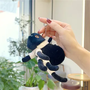 Cute black plush spider keychain accessory being held against a bright interior background