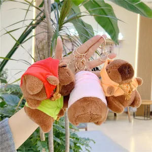 Detailed view of three capybara plush keychains wearing red, pink, and orange hoodies