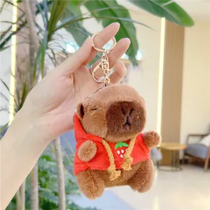Close-up of brown capybara plush keychain wearing a red strawberry hoodie with gold clasp
