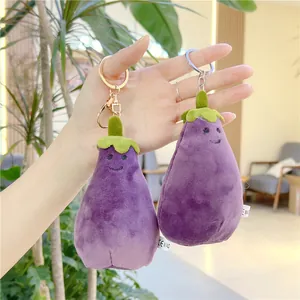 Close-up of a plush eggplant keychain with a smiling face and metal ring fasteners