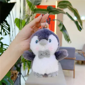 Detailed view of a soft grey plush penguin keychain with blue eyes and a cute bowtie