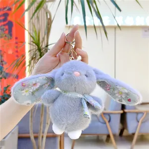Detail of grey plush bunny keychain with blue floral patterns held by hand