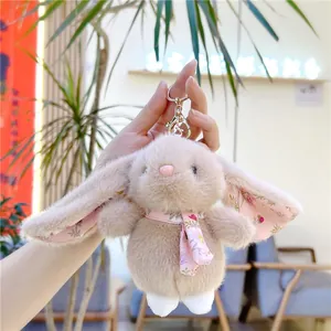 Detail of soft plush bunny keychain with pink floral scarf held by a hand