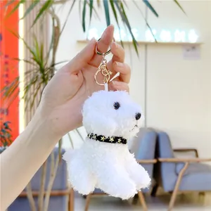 Plush white puppy keychain with gold clasp and black star collar held by model