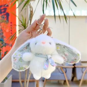 Close-up of white plush bunny keychain with floral fabric ears and silver metal hook