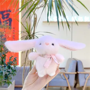 Detailed view of a soft pink plush bunny doll with a floral scarf held in hands