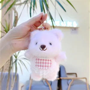 Detailed shot of pink plush bear keychain featuring a red checkered bib and lace trim