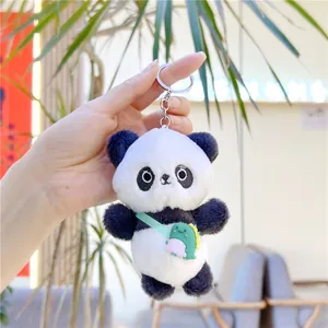 Close-up of cute panda plush keychain with a green dinosaur bag and silver metal ring
