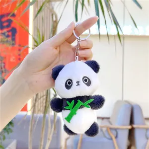 Close-up of cute panda plush keychain with green bamboo accessory held in hand