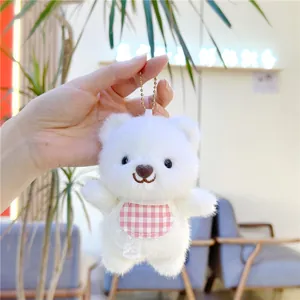 Detailed macro of white plush bear keychain with pink checkered lace bib and metal chain