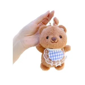 Brown plush bear keychain with blue plaid lace bib and gold chain on white background