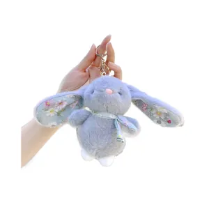 Grey plush bunny keychain with floral ear details and a golden clasp on white background