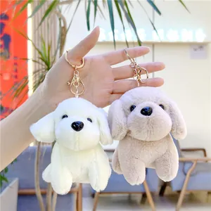 Detailed view of two cute plush dog keychains with fluffy fur and gold metal lobster clasps