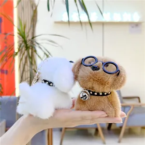 Detailopname van pluche honden-sleutelhangers met bril en bellen in wit en bruin