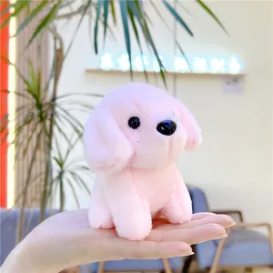 Close-up of small pink plush puppy keychain held in hand showing soft texture and mini size