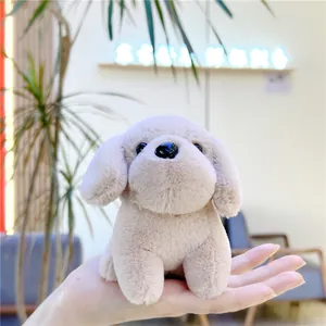 Close-up of a palm-sized beige plush puppy keychain made of soft polyester fiber