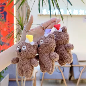 Nahaufnahme von drei braunen Teddybär-Schlüsselanhängern mit bunten Weihnachtsmützen
