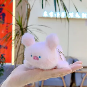Gros plan d'un porte-clés cochon en peluche rose douce tenu en main montrant sa texture