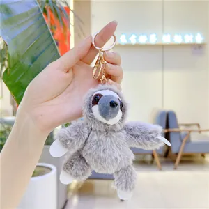 Detail of soft grey plush sloth keychain with gold metal lobster clasp and fluffy texture