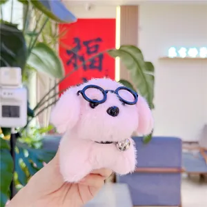 Close-up of a pink plush dog keychain featuring black round glasses and a metal bell accessory