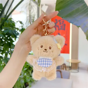 Close-up of cute plush brown bear keychain with blue plaid apron and golden clasp
