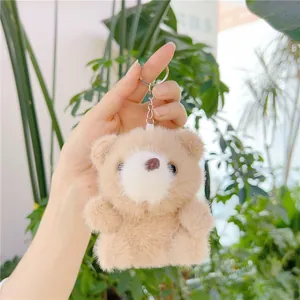 Primer plano del oso de peluche marrón claro con llavero de plata y textura muy suave