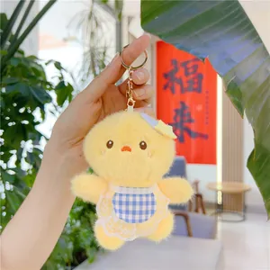 Detail of yellow plush chick pendant wearing a blue plaid apron with white lace trim