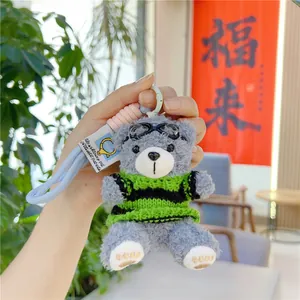 Makro-Detail von süßem Teddybär-Plüschanhänger mit Strickpullover und Schutzbrille