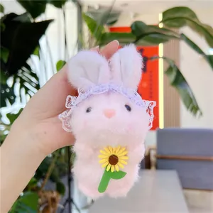 Detailopname van een roze pluche konijnenhanger met kant en een gele zonnebloem