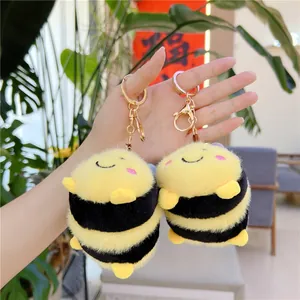 Portachiavi ape in peluche con strisce gialle e nere e chiusura dorata nella mano