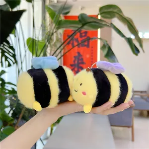 Dettaglio di portachiavi in peluche a forma di ape con strisce gialle tenuti in mano