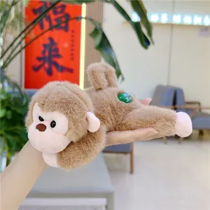 Detailed view of a small brown plush monkey toy with a green label held in a hand