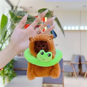 Plush Capybara keychain with a green frog swim ring and golden clip shown in hand