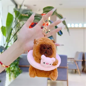 Close-up of plush capybara keychain with pink pig accessory and golden lobster clasp