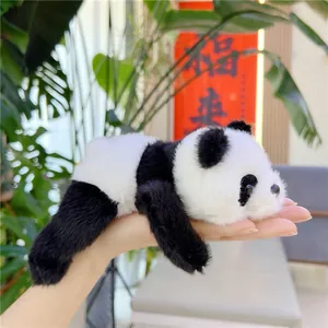 Close-up of a small plush panda toy lying in hand showing soft long faux fur texture