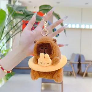 Detail of plush capybara keychain with a yellow ring and tiny bunny charm accessory