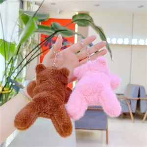 Cute plush monkey and bear keychains in pink and brown being held as bag charms