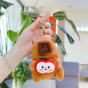 Detail of soft capybara plush keychain holding an apple with high-quality golden ring