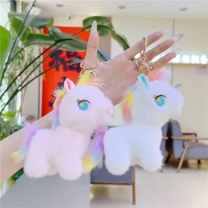 Macro shot of cute plush unicorn keychains in pink and white with gold metal clips