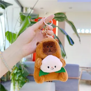Close-up of plush capybara keychain holding a pink peach with gold lobster clasp