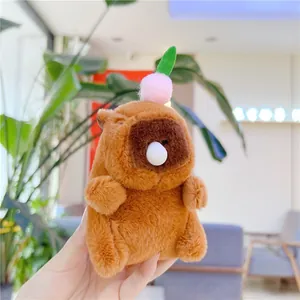 Close-up of cute plush capybara keychain with a pink pompom and green leaf detail
