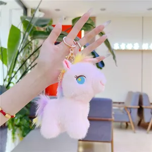 Close-up of pink unicorn plush keychain with starry eyes and golden metal keyring clasp